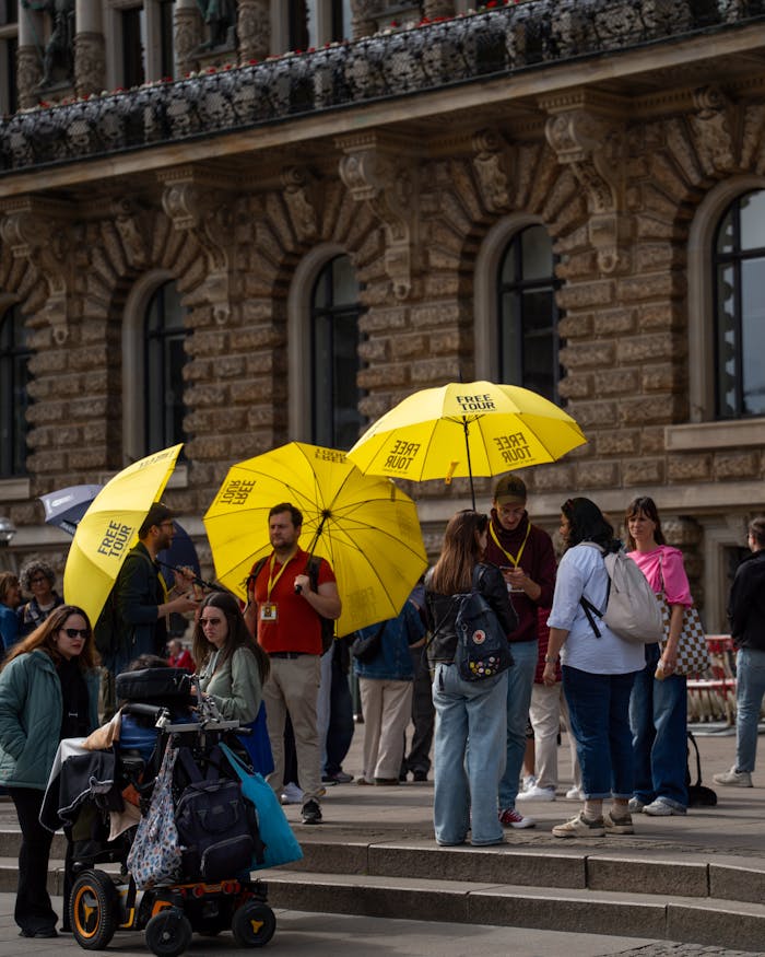 Group of tourists with yellow free tour umbrellas in a city center.
